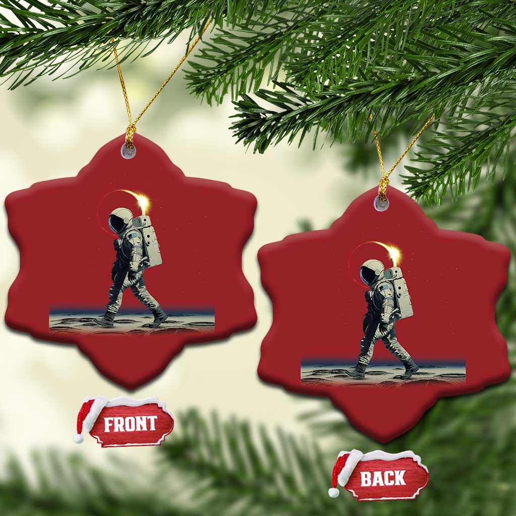 Two red heart-shaped astronaut ornaments with gold hangers hanging on a tree