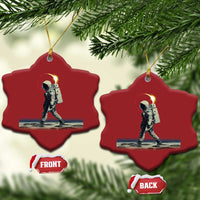 Two red heart-shaped astronaut ornaments with gold hangers hanging on a tree