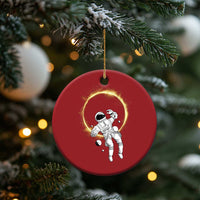 Red circular astronaut ornament with glowing halo ring, hanging from a gold string