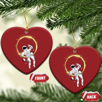 Two red heart-shaped astronaut ornaments with glowing halo rings hanging from gold strings