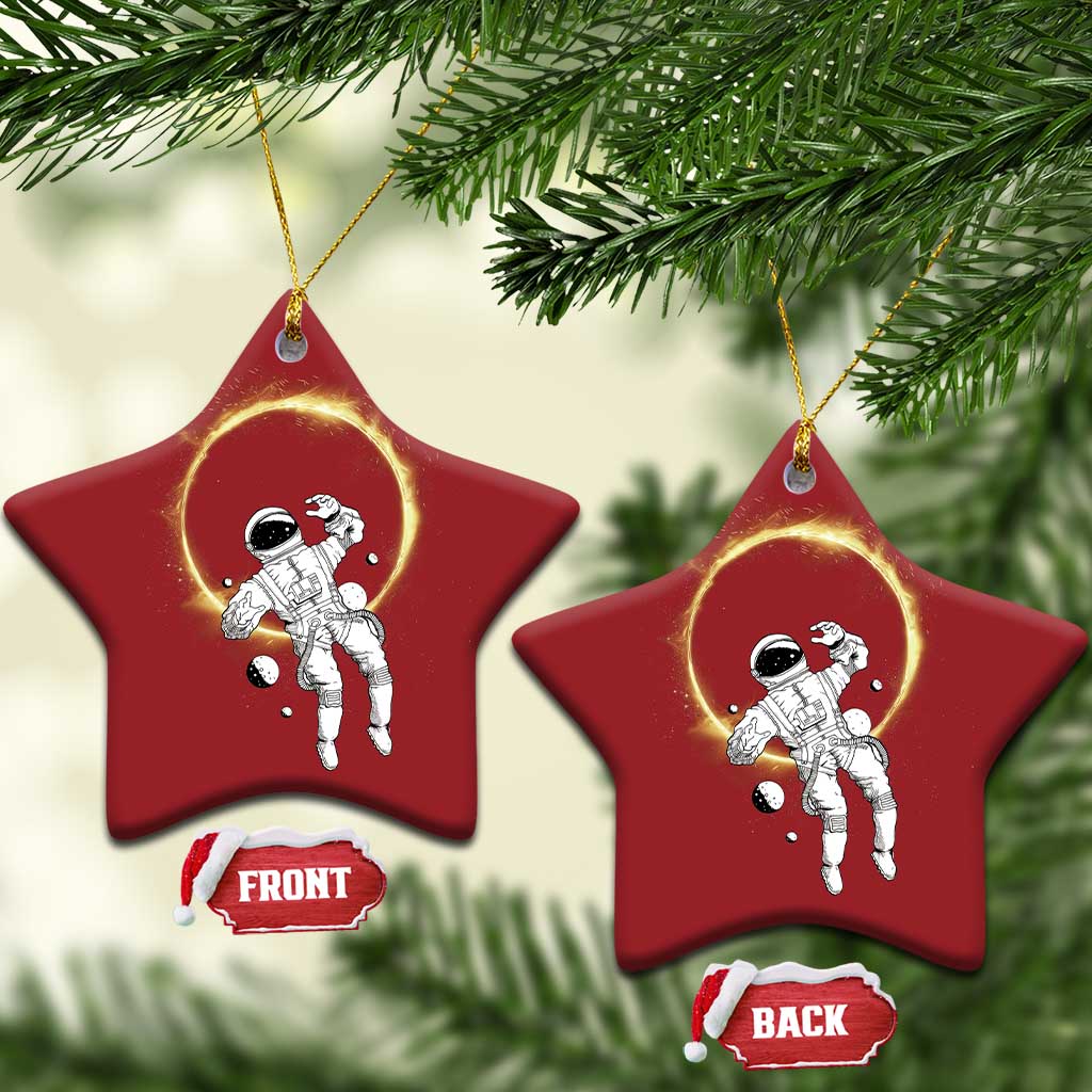 Two red star-shaped astronaut ornaments with glowing halo rings hanging from gold strings