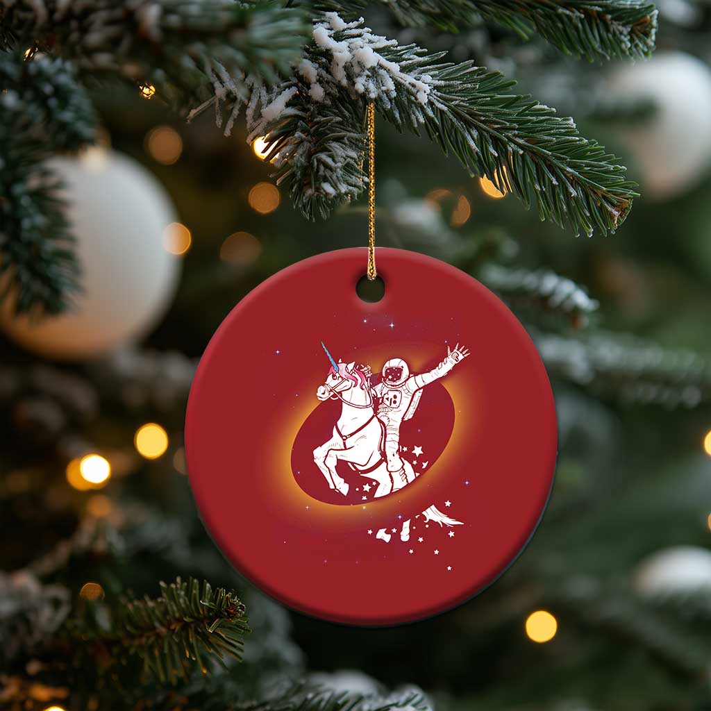 Red round Christmas ornament featuring astronaut riding unicorn with starry accents