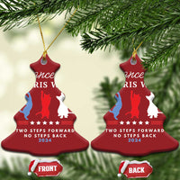 Two red bell-shaped Christmas ornaments with dancer silhouettes and front/back labels on pine