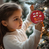 Red round Christmas ornament with “it starts with hello” greeting text hanging from gold string.