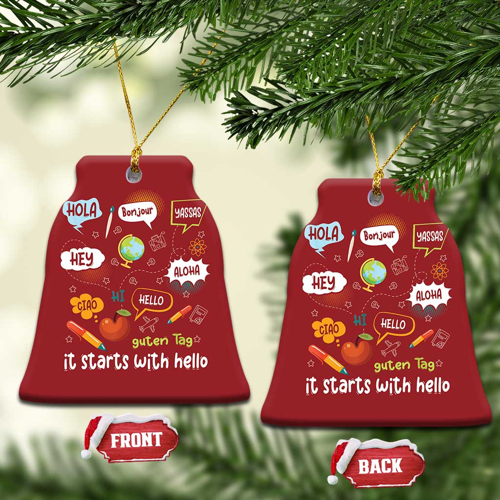 Two red bell-shaped Christmas ornaments with multilingual “it starts with hello” text, gold strings.