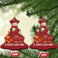 Two red bell-shaped Christmas ornaments with “it starts with hello” and language greetings, gold strings.