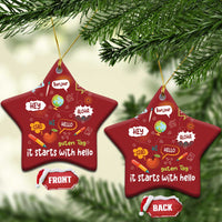 Two red star-shaped Christmas ornaments with “it starts with hello” multilingual greetings, gold strings.