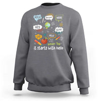 Inclusion Matters sweatshirt, charcoal crewneck with colorful multilingual “it starts with hello” graphic