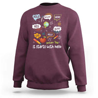Inclusion Matters sweatshirt, maroon crewneck with colorful multilingual “it starts with hello” graphic