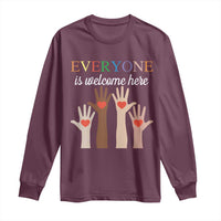 Maroon long sleeve shirt with “Everyone is welcome here” heart-hand graphic