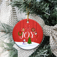 Round red ceramic ornament with “JOY” design hanging on Christmas tree.