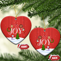 Red heart-shaped ceramic ornaments with “JOY” scene, gold hanging loops, front/back labels.