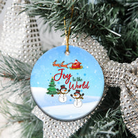 Blue ceramic circular ornament hanging on a tree, Joy to the World with snowmen.