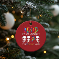 Red round ADHD awareness ornament hanging on pine branch, colorful ADHD text and skulls.