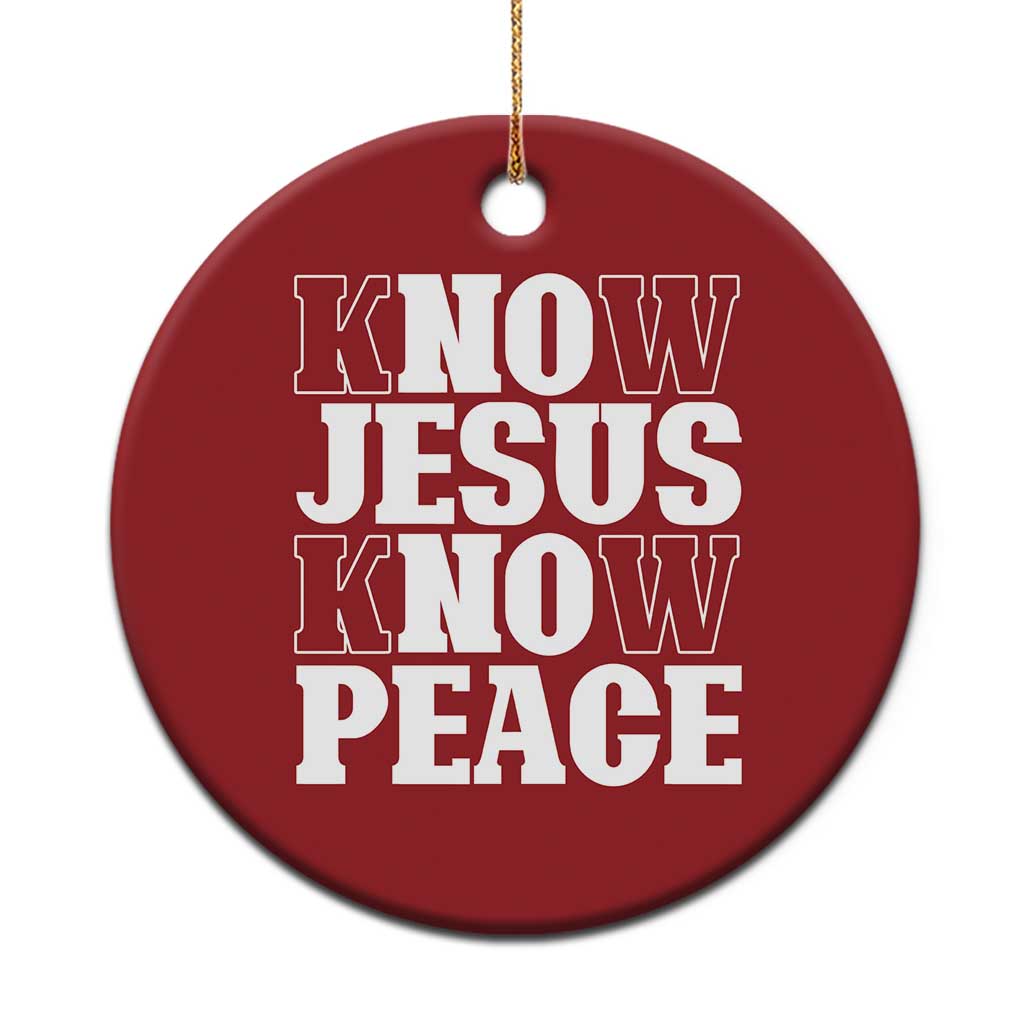 Red circular Christmas ornament with white text: “KNOW JESUS KNOW PEACE,” gold hanging string.