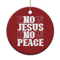 Red circular Christmas ornament with white text: “KNOW JESUS KNOW PEACE,” gold hanging string.