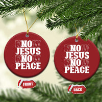 Two red circular Christmas ornaments on green branches, “KNOW JESUS KNOW PEACE” text; gold strings.