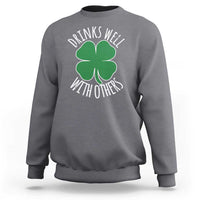Charcoal crewneck sweatshirt with green shamrock graphic and 'Drinks well with others' text
