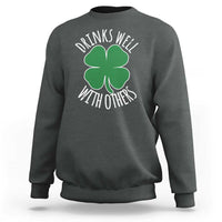 Dark heather crewneck sweatshirt with green shamrock graphic and 'Drinks well with others' text
