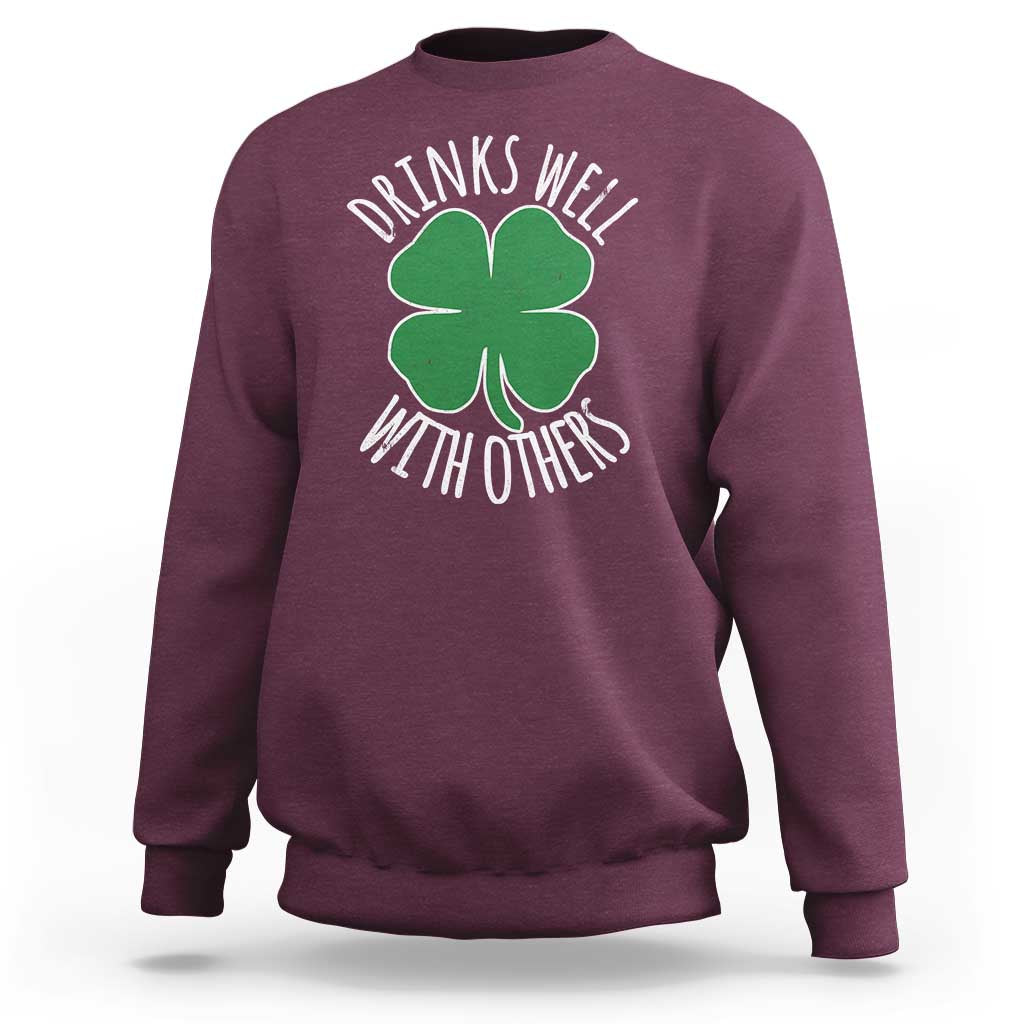 Maroon crewneck sweatshirt with green shamrock graphic and 'Drinks well with others' text