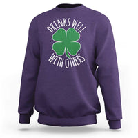Purple crewneck sweatshirt with green shamrock graphic and 'Drinks well with others' text