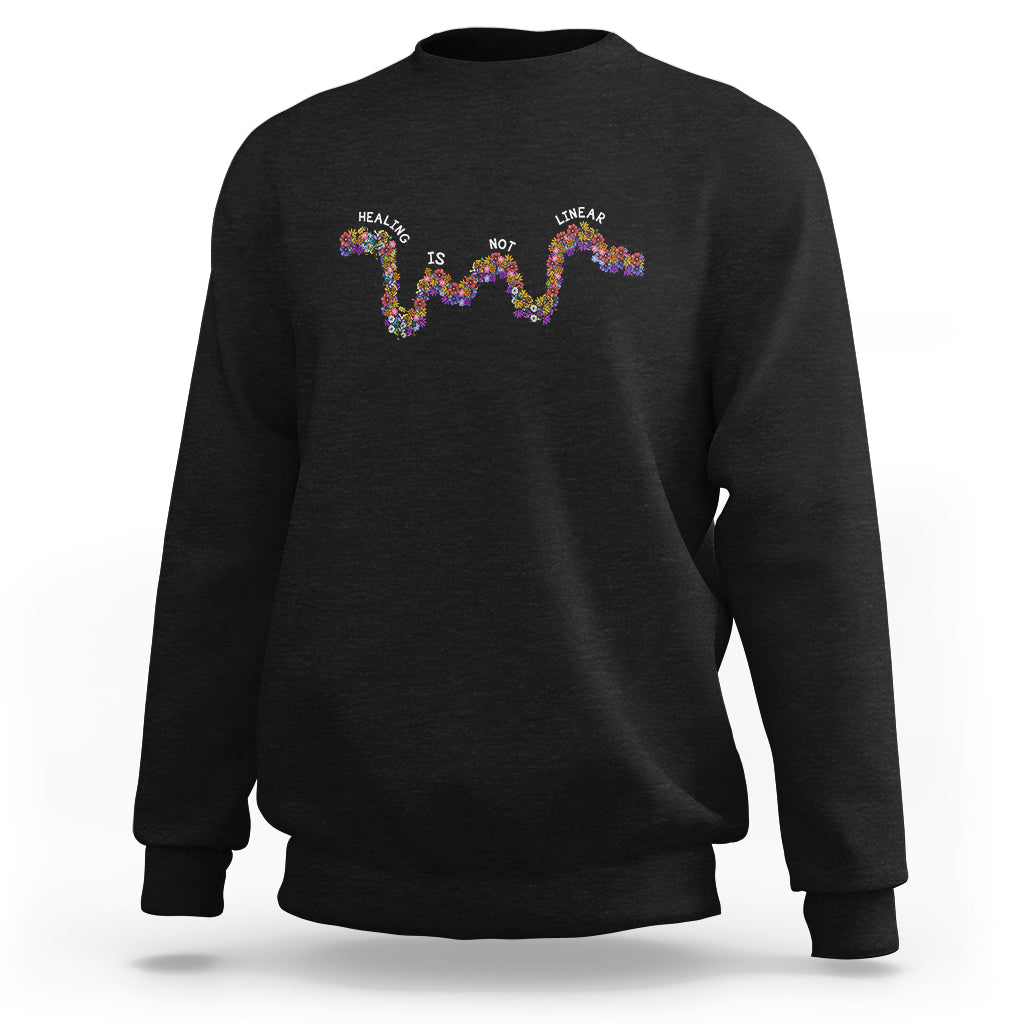Black sweatshirt with colorful “Healing is not linear” graphic on back