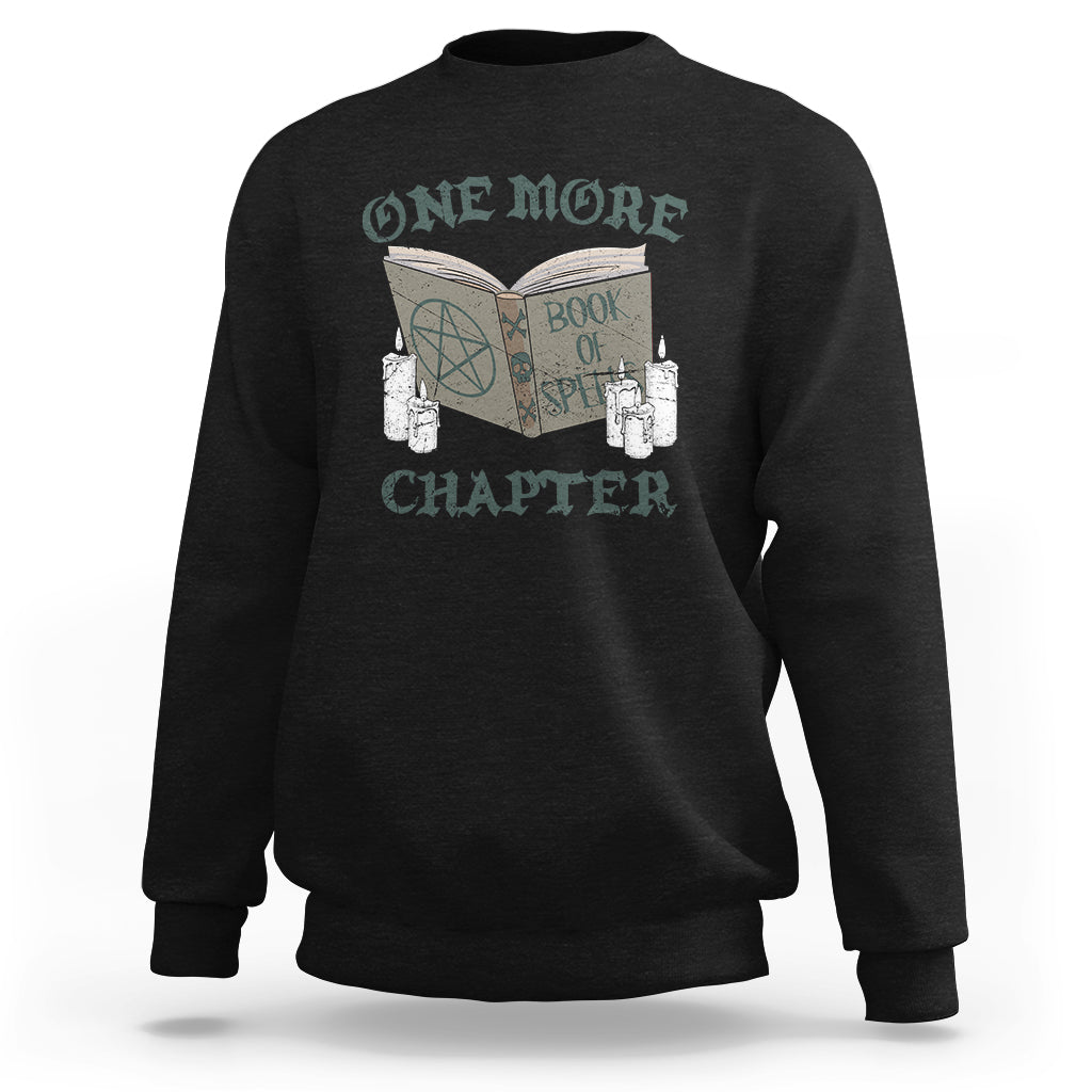 Black sweatshirt with front graphic of an open book, candles, and “ONE MORE CHAPTER”