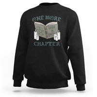 Black sweatshirt with front graphic of an open book, candles, and “ONE MORE CHAPTER”