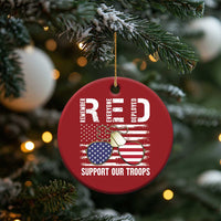 Red round Christmas ornament hanging from pine branch, eagle and U.S. flag with "Support Our Troops"
