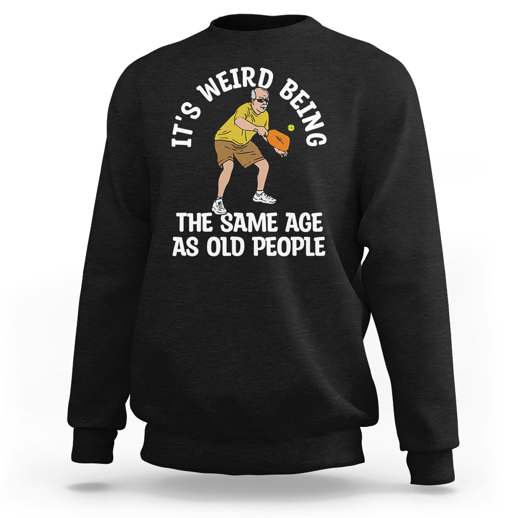 Black crewneck sweatshirt with pickleball graphic and the phrase “THE SAME AGE AS OLD PEOPLE”.