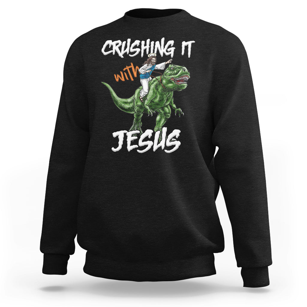 Black crewneck sweatshirt with dinosaur graphic and text "CRUSHING IT with JESUS"