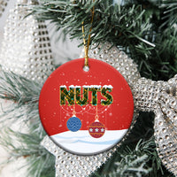 Red ceramic round Christmas ornament with “NUTS,” hanging from a gold string.