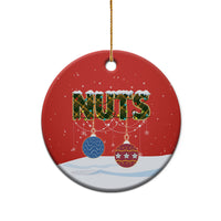 Red ceramic round Christmas ornament with “NUTS” design, shown centered with gold string.