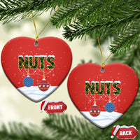 Red ceramic heart-shaped Christmas ornament with “NUTS,” hanging by gold string.