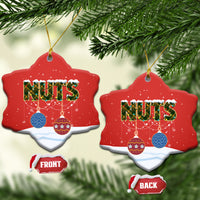 Red ceramic Christmas tree-shaped Christmas ornament with “NUTS,” hanging from gold string.