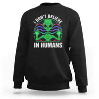 Black crewneck sweatshirt with green alien graphic and “I don’t believe in humans” text