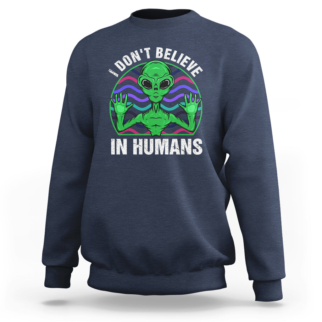Navy crewneck sweatshirt with green alien graphic and “I don’t believe in humans” text
