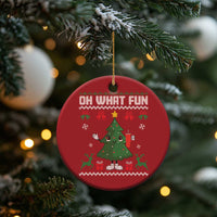 Red round "Oh What Fun" ornament hanging from pine branches with cartoon tree