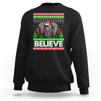 Black Christmas sweatshirt with mothman graphic and bold “BELIEVE” text