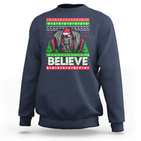 Navy Christmas sweatshirt with mothman graphic and bold “BELIEVE” text