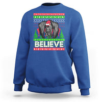 Royal blue Christmas sweatshirt with mothman graphic and bold “BELIEVE” text