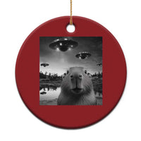 Red round Christmas ornament with capybara and UFO graphic, hanging loop at top