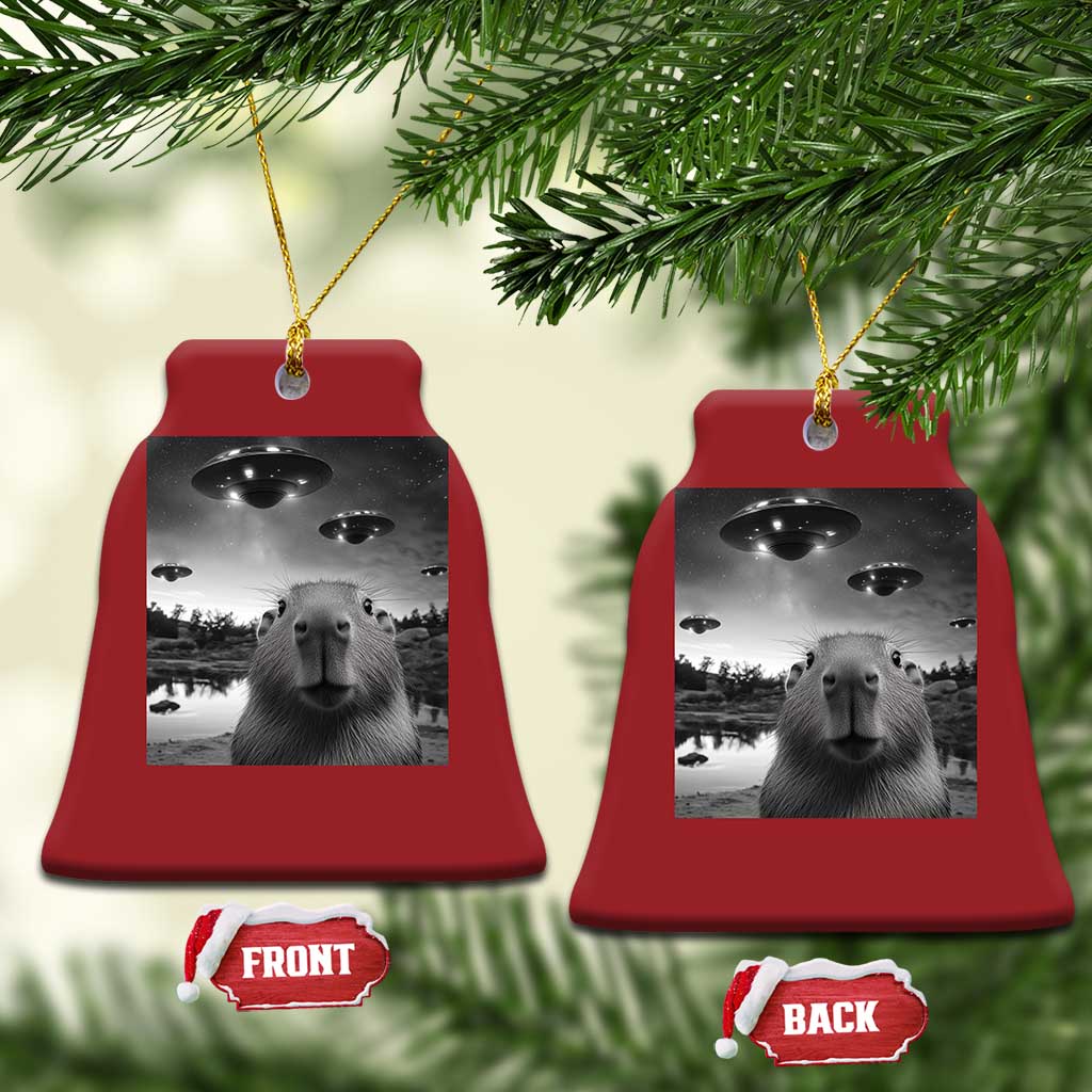 Two red bell-shaped Christmas ornaments with capybara and UFO graphic, front/back tags
