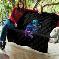 Black quilt draped on sofa with multicolor skull-and-text graphic, diamond stitching