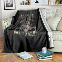 Black blanket with skull slogan graphic, draped over striped sofa back