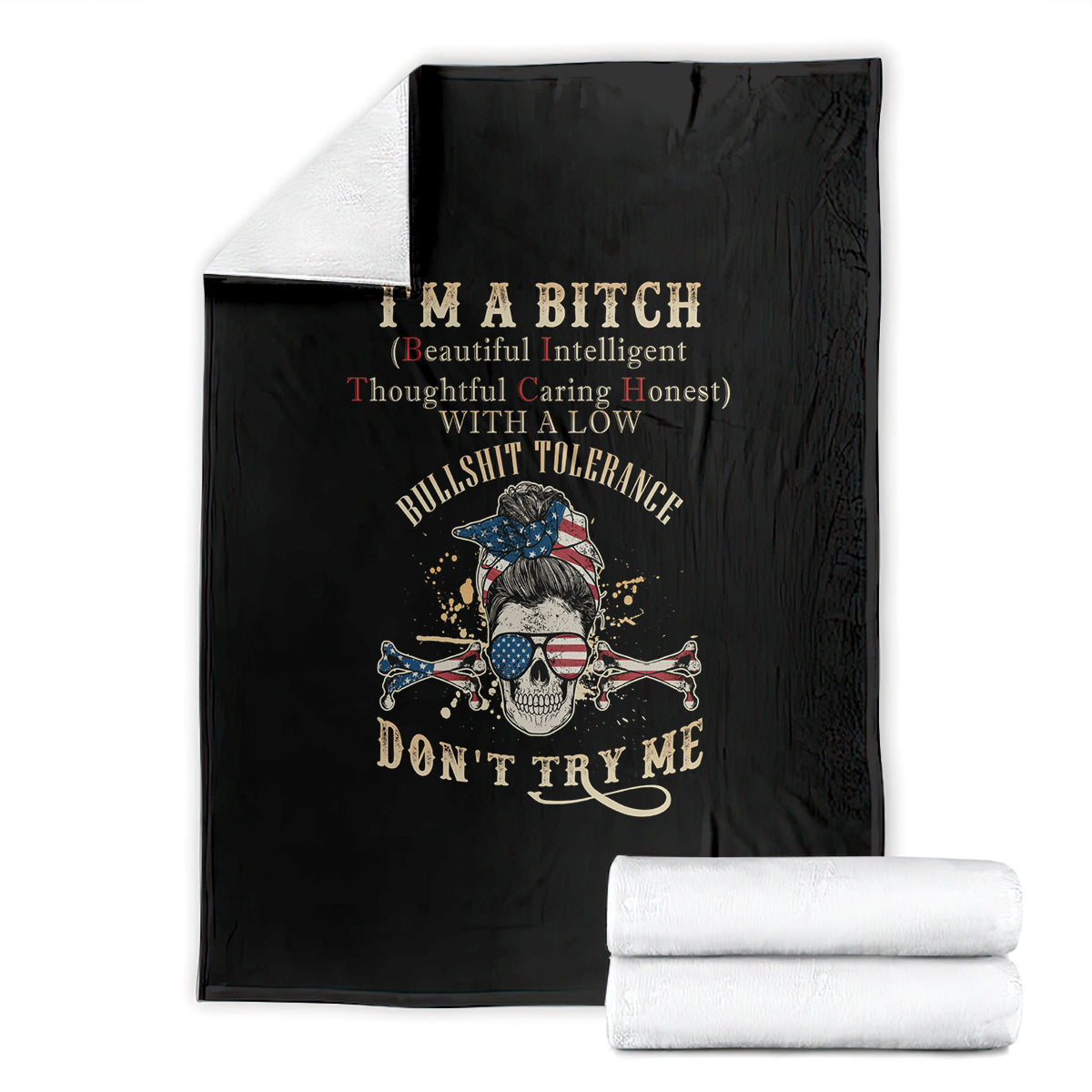 Black blanket with skull graphic and text, folded with stacked white towels