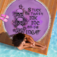 Round purple beach blanket with fringed edge, skull and roses graphic with text