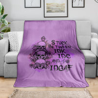 Purple graphic throw blanket with skull-and-rose typography design, draped over couch