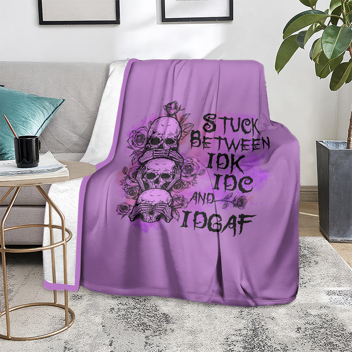Purple graphic blanket with skull-and-rose typography design, laid on floor with couch