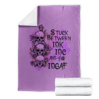 Purple graphic blanket with skull-and-rose text design, folded with matching white towels